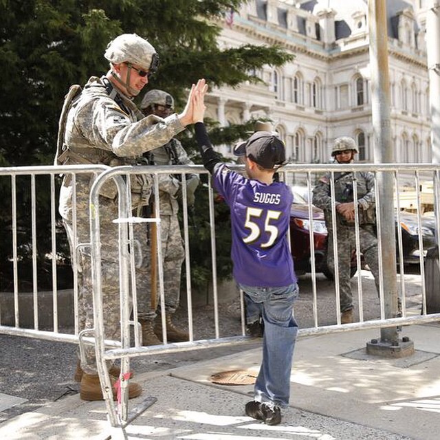Maryland National Guard soldier and Baltimore boy high-five while talking about sports outside City Hall on Tuesday. (Mike Morones/Army Times)